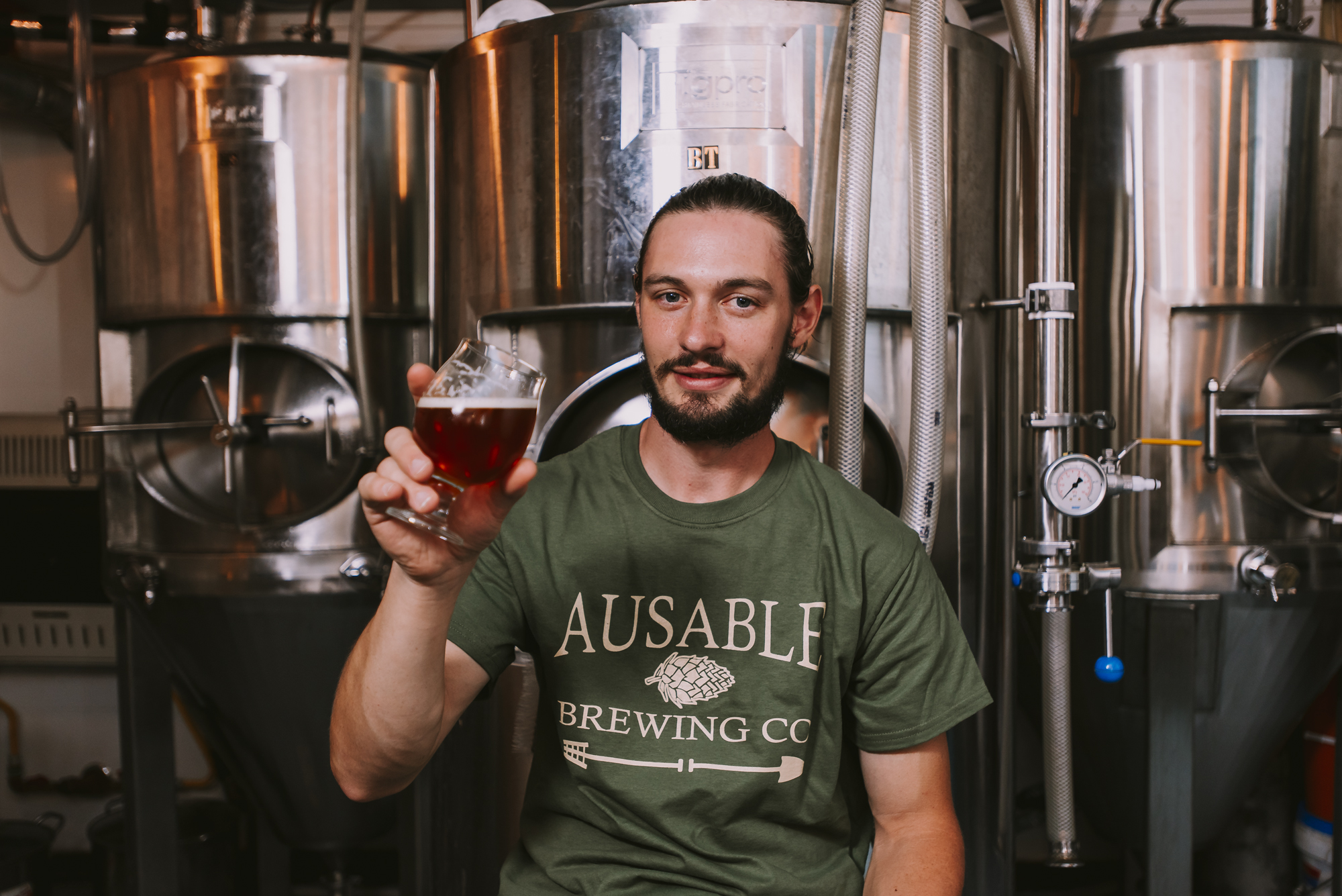brewer holding up fresh craft beer at Ausable Brewing Company