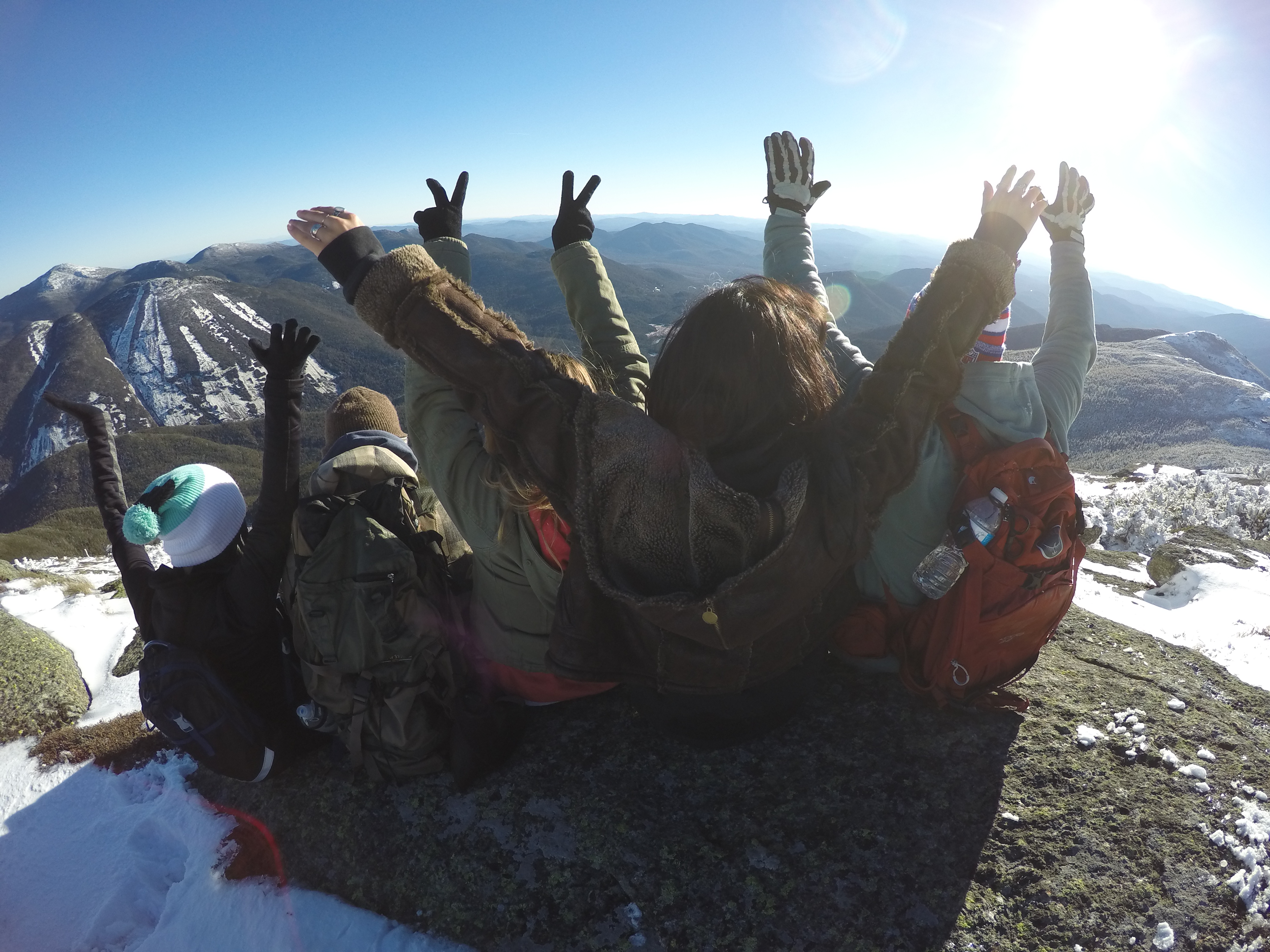 group of friends celebrating at top of mountain after winter hiking