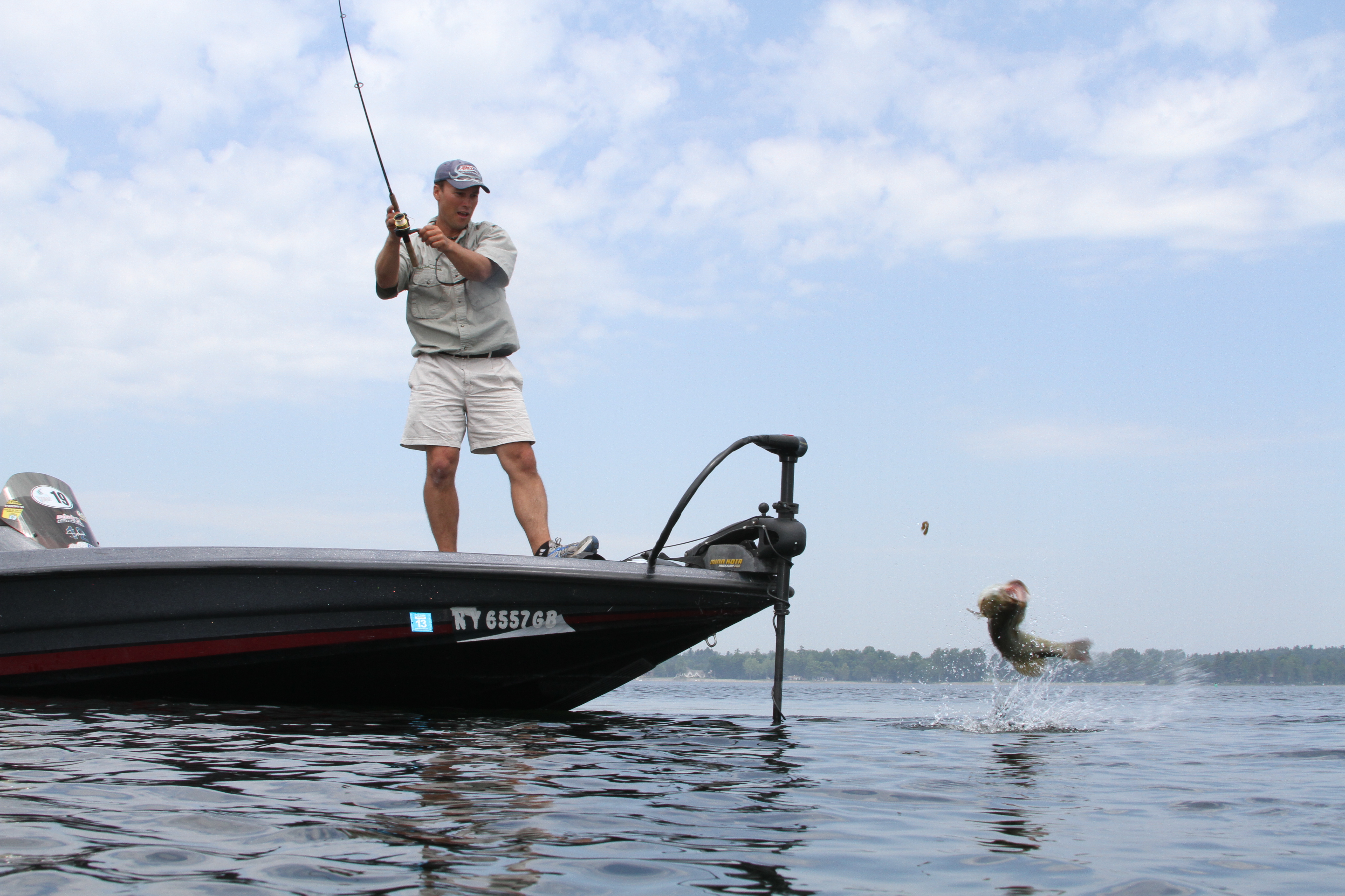 man standing on boat fishing in the Adirondacks