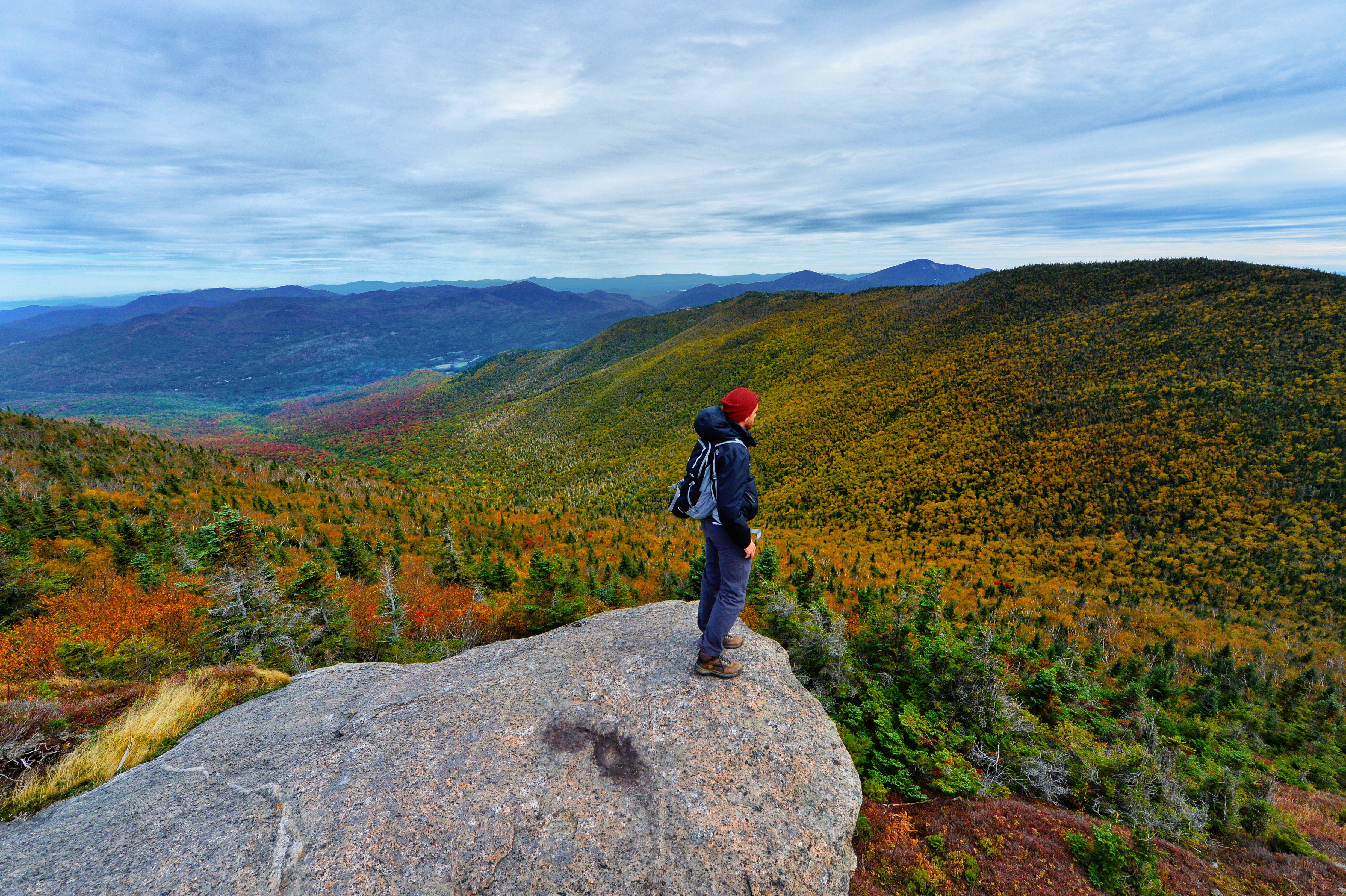 man looking out at Fall foliage in the Adirondacks during a fall hike