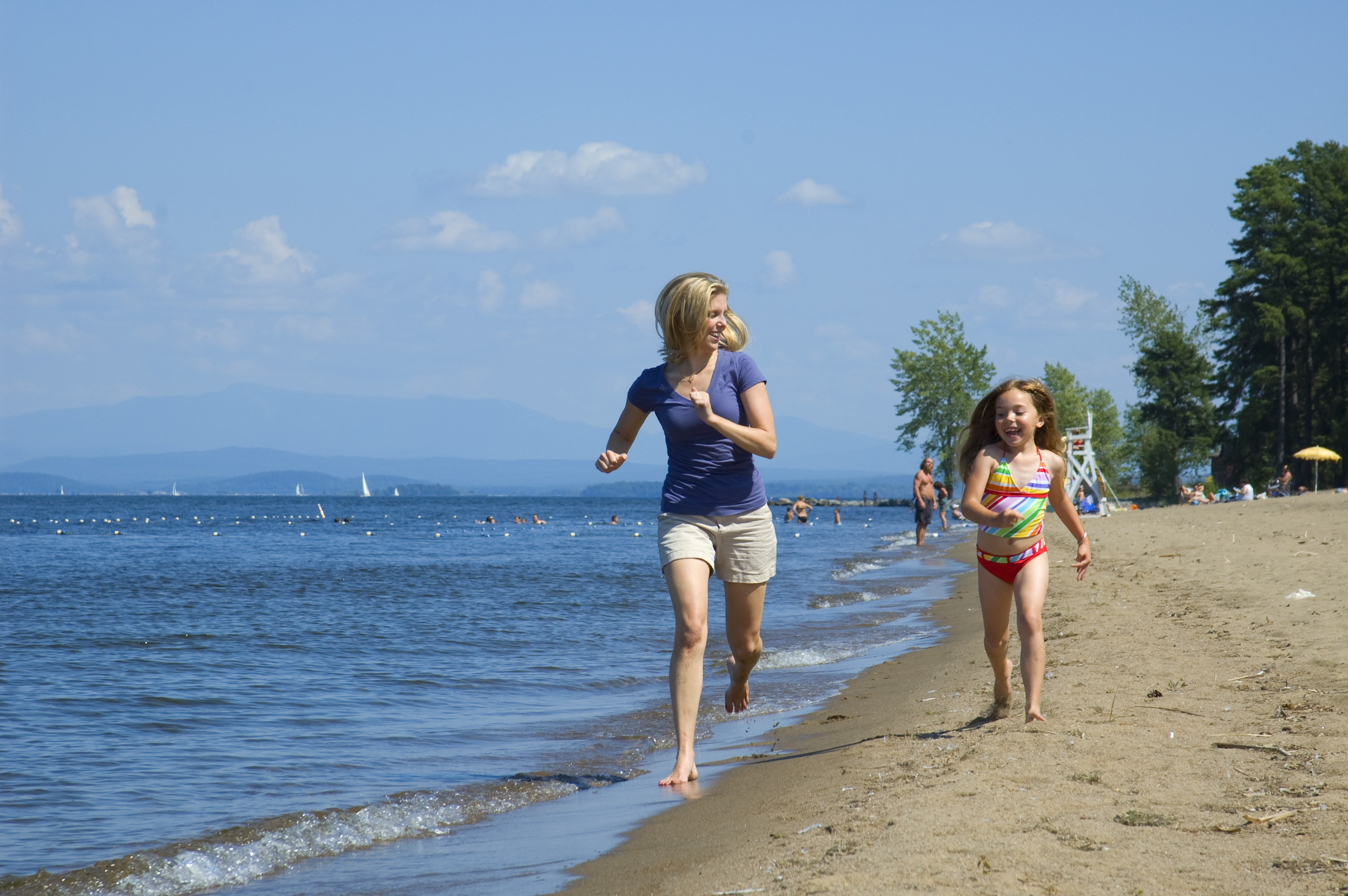 mother and daughter running on a beach of Lake Champlain
