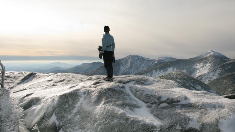 person at top of a mountain during a winter hike in the Adirondacks
