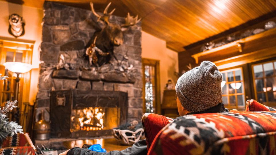 man enjoying fireplace in an Adirondack cabin