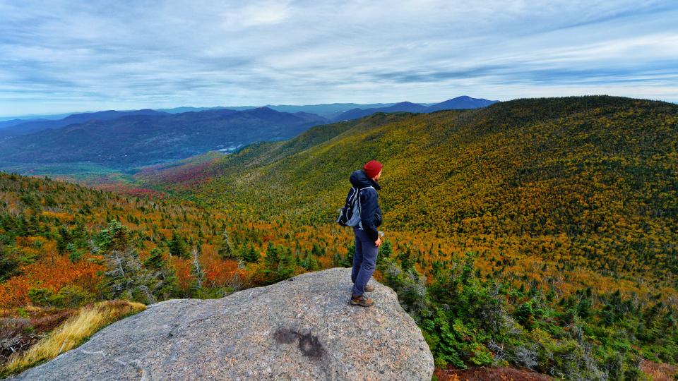 man looking out over the fall foliage during an Adirondack fall hike