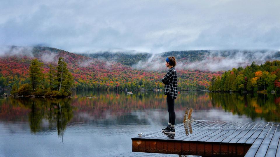 Girl on dock in with fall colors in the background 