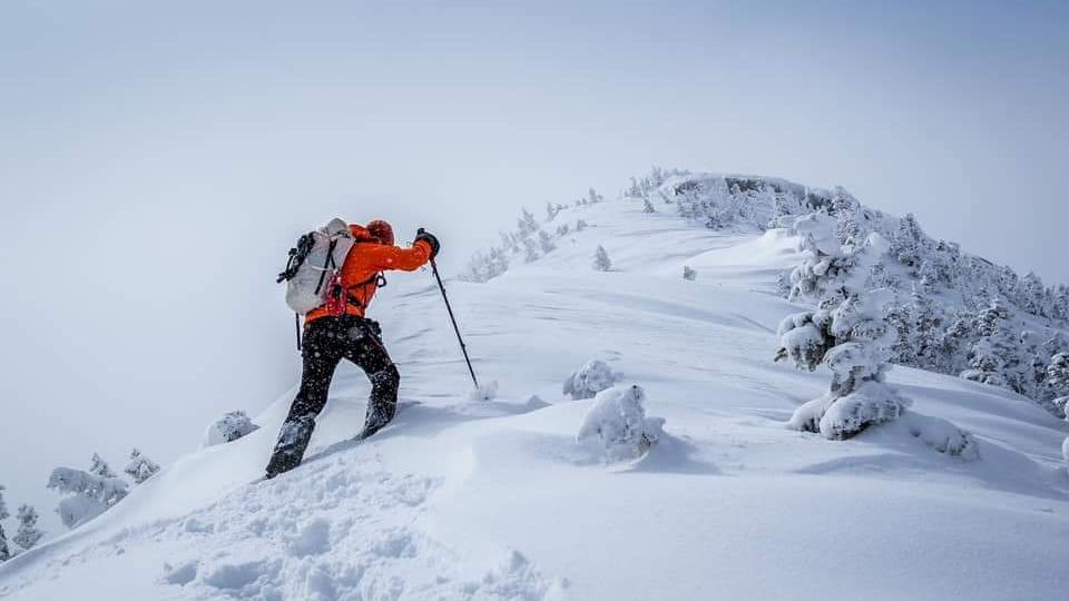 man hiking a mountain in the Adirondacks during winter