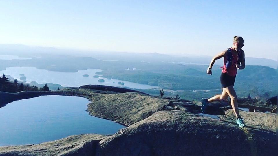 female running in the Adirondacks at top of Mountain
