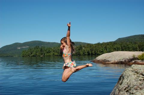 little girl jumping into a pond