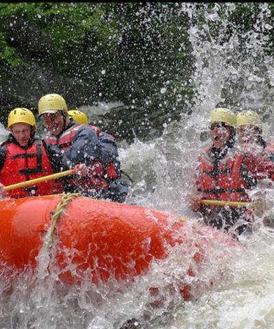 people getting splashed while whitewater rafting in the Adirondacks
